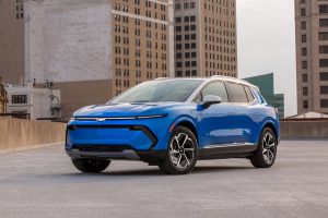 Front 3/4 view of a 2024 Chevrolet Equinox EV LT in Riptide Blue Metallic with a Summit White roof parked on the roof of a parking garage.